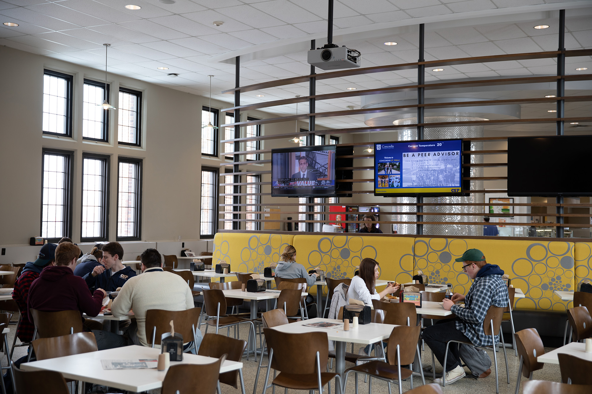 Campus dining hall with students eating at tables.