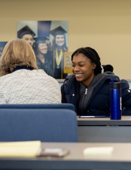 Student sitting at a table with a staff member and smiling.
